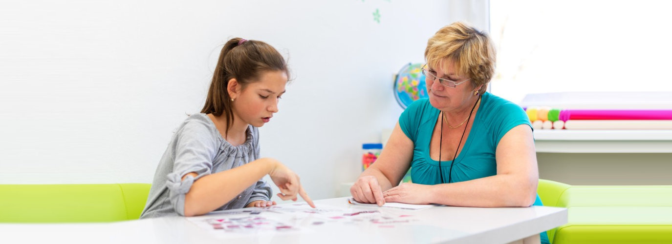 adult woman working with a teenage girl with learning difficulties to master logical tests