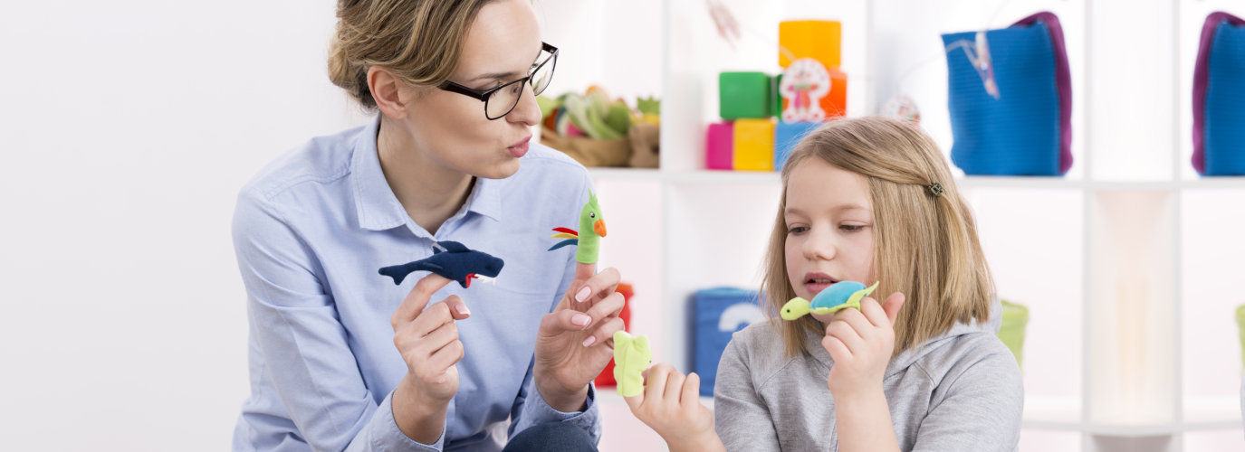 Female teacher using colorful toys during play therapy with child